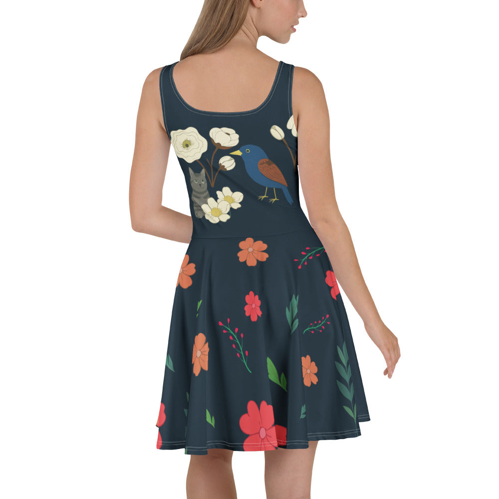Jeune femme portant une robe patineuse bleu marine à fleurs, oiseaux et chat dessiné