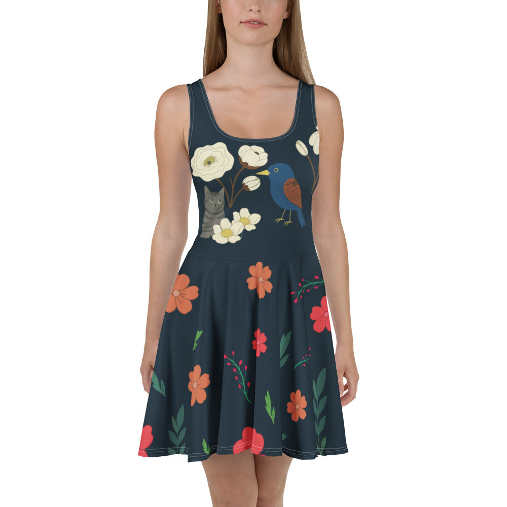 Jeune femme portant une robe patineuse bleu marine à fleurs, oiseaux et chat dessiné